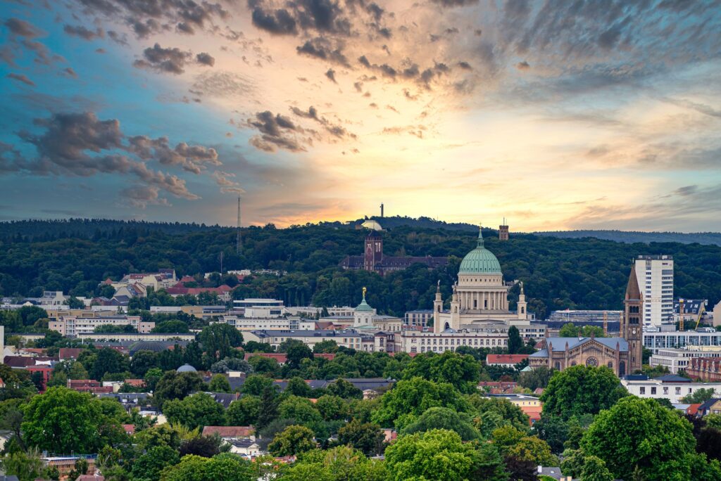 Blick über Potsdam bei Sonnenuntergang mit Kirchenkuppel, Grünflächen und Altstadt - Symbol für würdevolle Bestattung in Brandenburg.