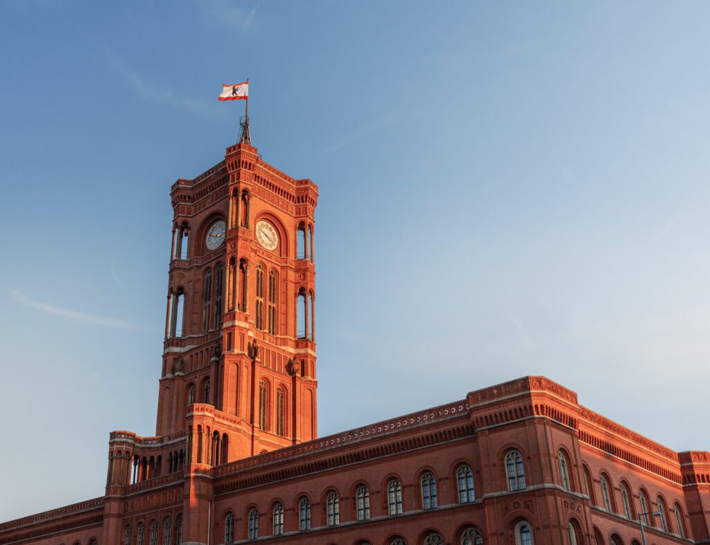 Rotes Backsteingebäude mit Uhrturm und Flagge, steht für vertrauensvolle und würdevolle Bestattungen in Berlin.