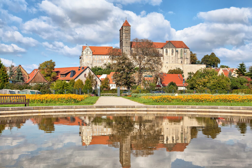 Schloss mit rotem Dach spiegelt sich im Teich, umgeben von Natur - Symbol für Ruhe und Würde bei Bestattungen deutschlandweit.