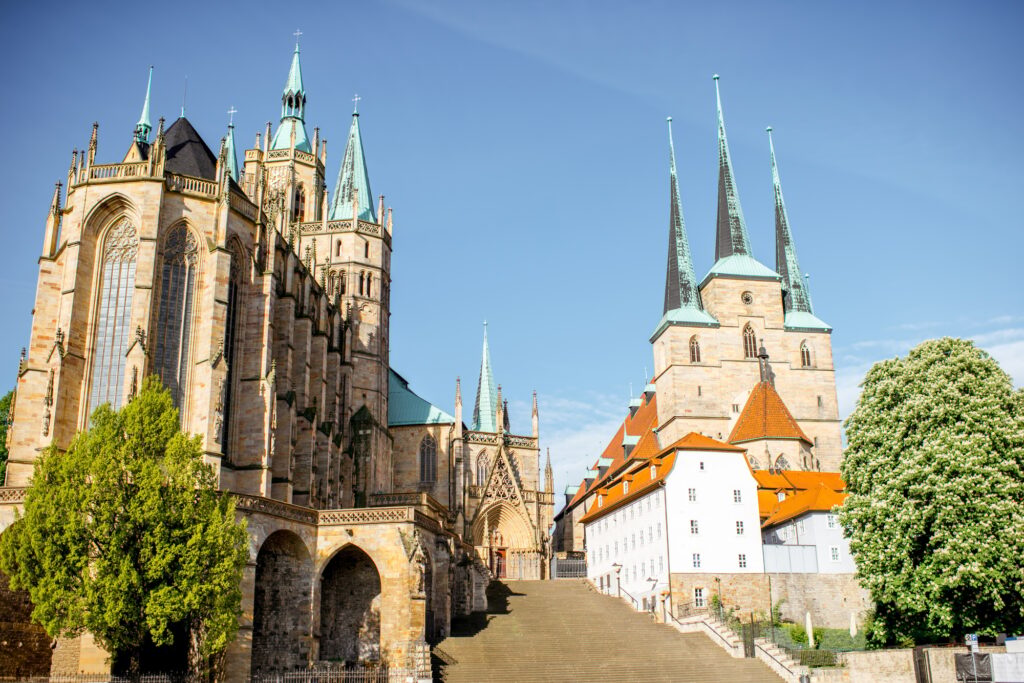 Gothische Kathedrale mit Kirche, steinernen Stufen und Bäumen - Sinnbild für würdevolle Bestattung in Deutschland.