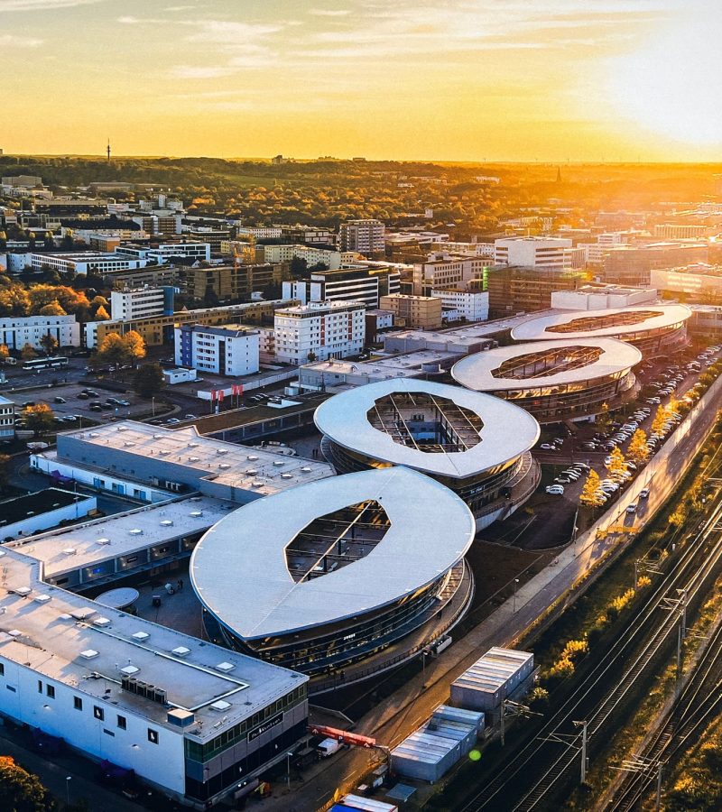 Moderne Stadtansicht bei Sonnenuntergang mit weißen Gebäuden und Bahnhof - Symbol für deutschlandweite YANA Bestattungen.